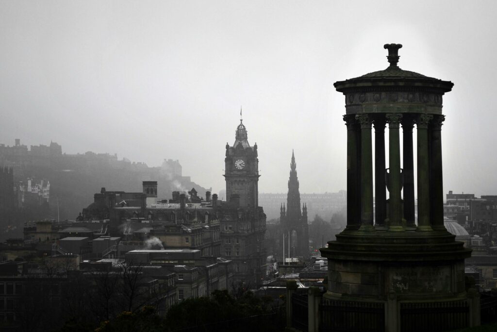 A scenic view of Edinburgh's iconic Calton Hill under grey skies, featuring historic monuments.